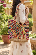 Adult woman carrying the multicolor braided tote in a sunlit heritage courtyard garden