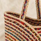 Angled close-up of the tote bag long braided handle and colorful top edge